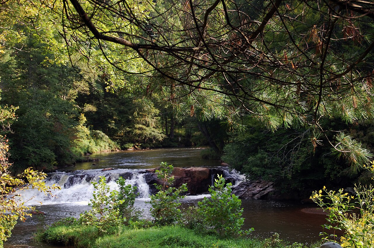 Waterfall along Chestnut Creek framed by pine branches on the New River Trail in Galax, Virginia.