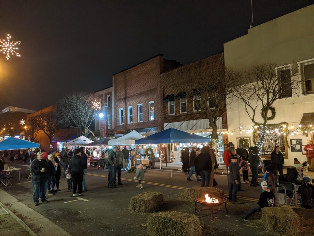 Festivalgoers gathered around a fire pit on Main Street during the 2024 Old Time Appalachian Christmas Festival in Galax.